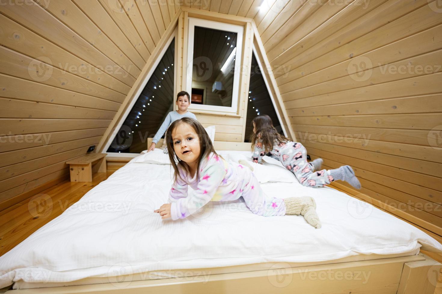 bambini nel morbido caldo pigiama giocando a di legno cabina casa. concetto di infanzia, tempo libero attività, felicità. fratello e sorelle avendo divertimento e giocando insieme. foto