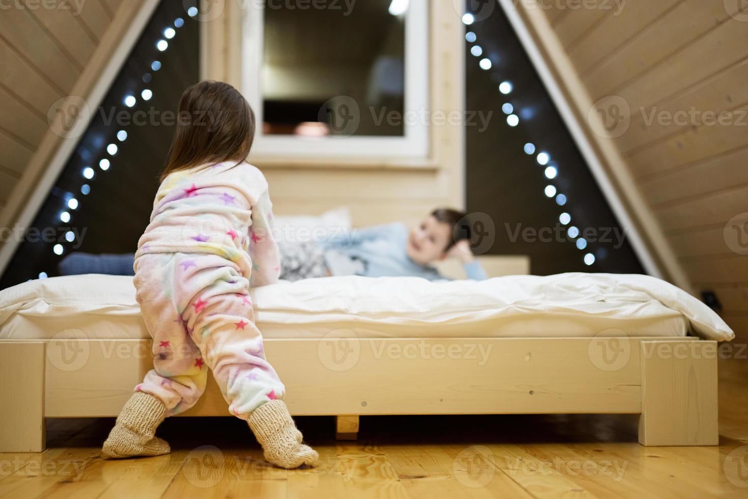 bambini nel morbido caldo pigiama giocando a di legno cabina casa. concetto di infanzia, tempo libero attività, felicità. fratello e sorella avendo divertimento e giocando insieme. foto