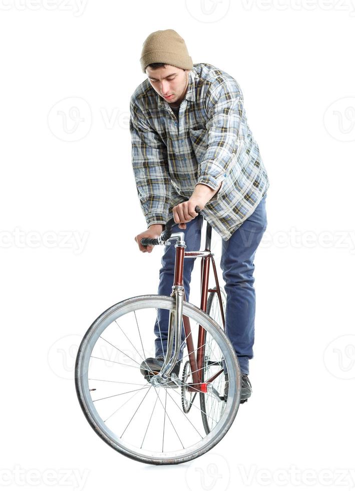 giovane uomo fare trucchi su fisso Ingranaggio bicicletta su un' bianca foto