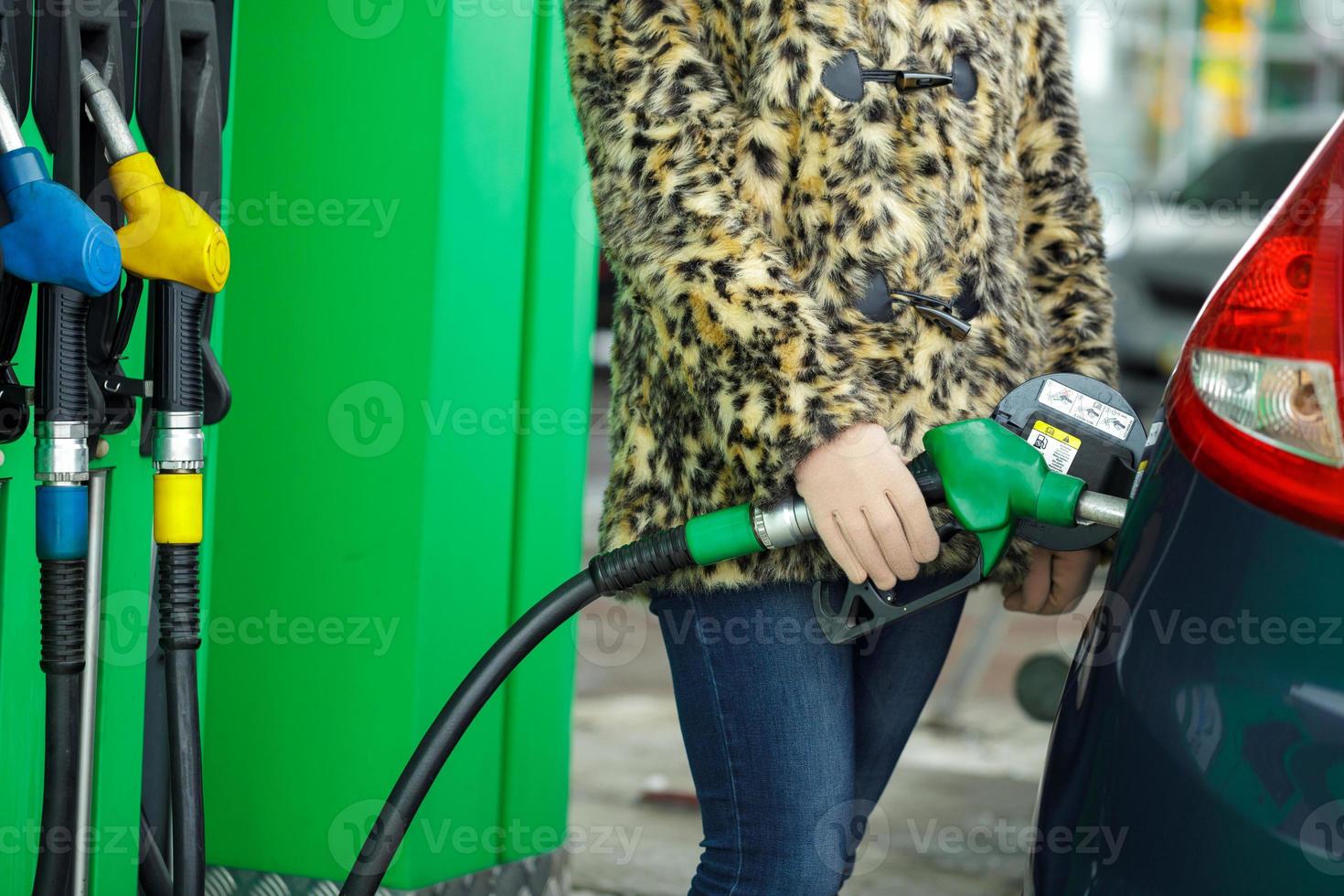 donna riempimenti benzina in sua auto a un' gas stazione nel inverno foto