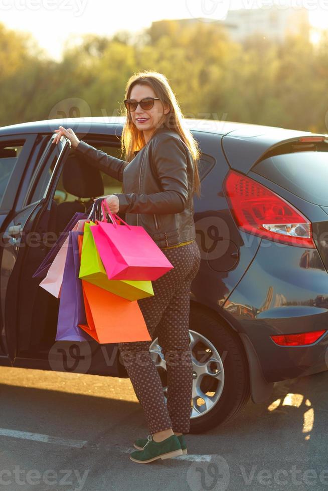 sorridente caucasico donna mettendo sua shopping borse in il auto - shopping concetto foto