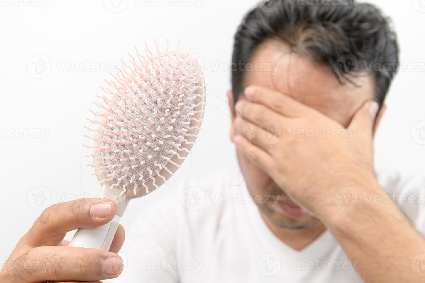 di mezza età uomo Spettacoli pettine spazzola con perdita capelli e stressato di il suo capelli perdita i problemi foto