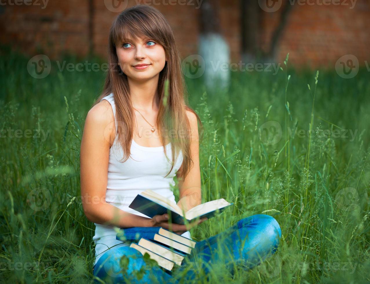 giovane bellissimo ragazza con libro nel il parco su verde erba foto