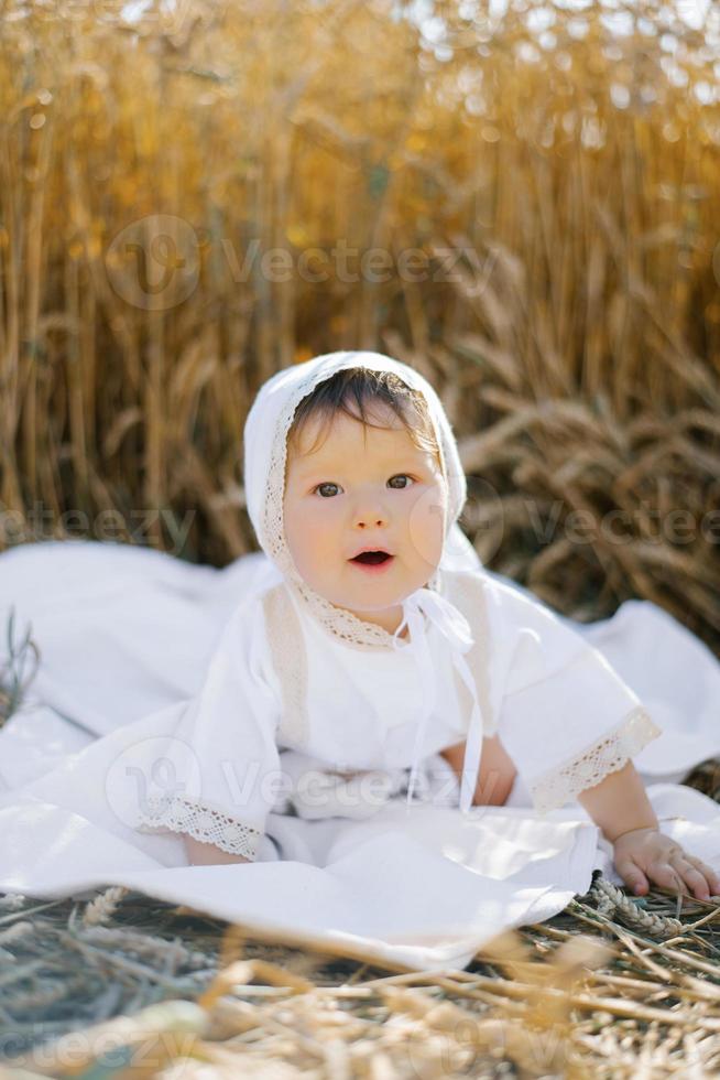 un' bambino ragazzo nel bianca Abiti è rilassante nel il fresco aria nel un' campo foto