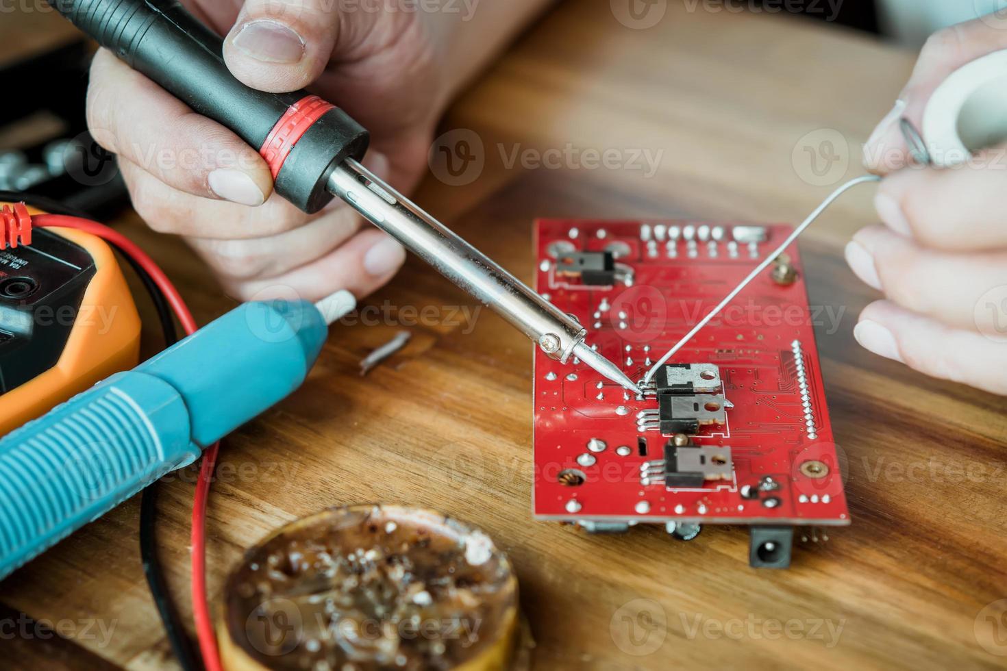 tecnico uomo Tenere ferro saldare e riparazione il circuito tavola di saldatura. elettrico opera concetto foto