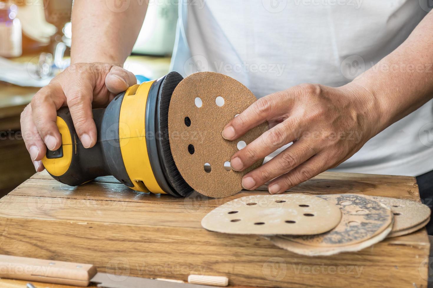 falegname allegare carta vetrata per un orbitale levigatrice o palma levigatrice dopo rimuovere il carta sostegno di il carta vetrata.fai da te creatore e la lavorazione del legno concetto. selettivo messa a fuoco foto