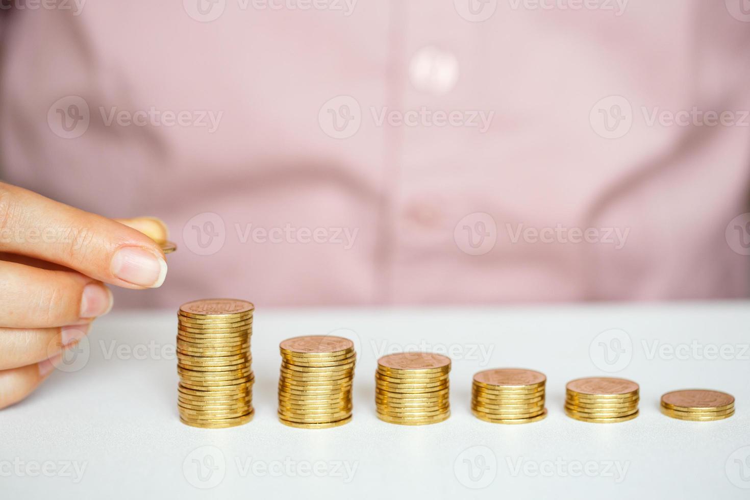femmina mano impilamento oro monete in crescente colonne foto