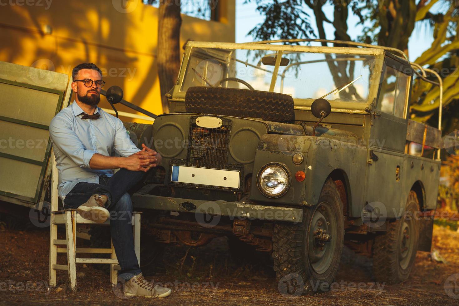 giovane elegante uomo con bicchieri e arco cravatta vicino il vecchio stile suv foto