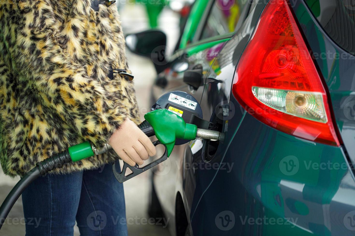 donna riempimenti benzina in sua auto a un' gas stazione nel inverno foto