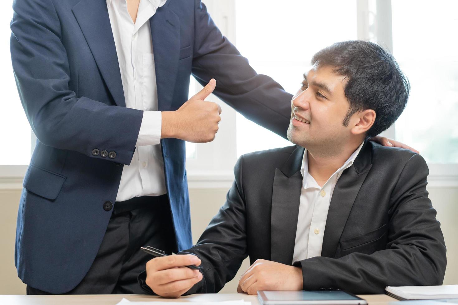 congratularsi, fiducia Due collega asiatico uomo d'affari, maschio incoraggiare personale per fatto eccellente opera. capo mostrando pollici su per fare molto bene lavoro. comando di squadra sostegno. fiducia di supervisore. foto