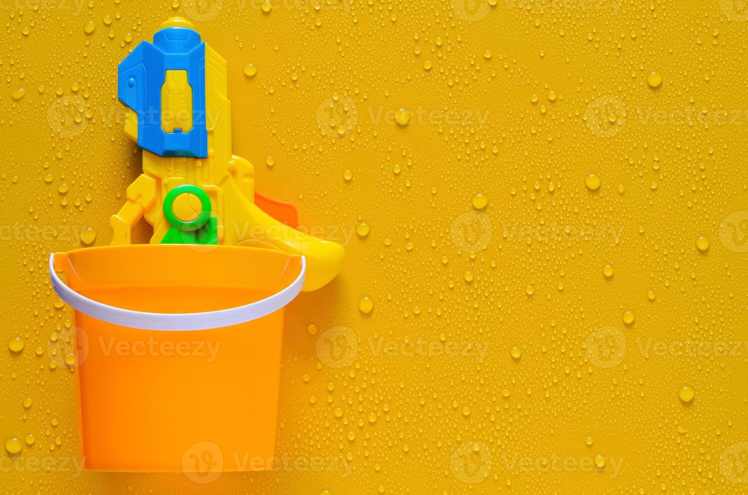 acqua pistola nel secchio su bagnato giallo sfondo per Tailandia Songkran Festival concetto. foto