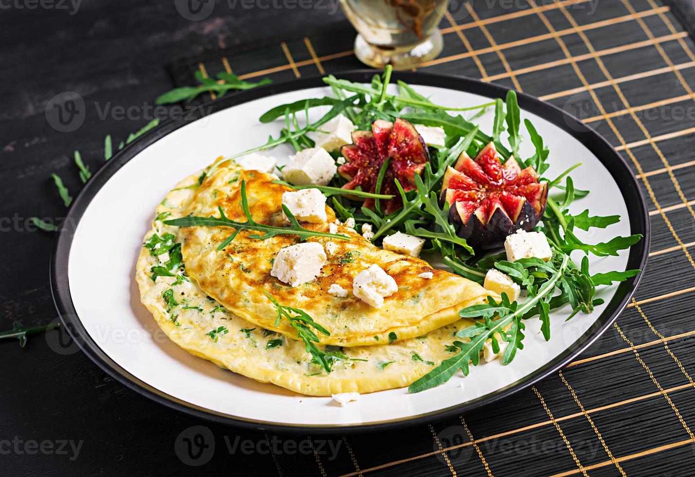 frittata con feta formaggio, prezzemolo e insalata con fichi, rucola su bianca piatto. frittata - italiano frittata. foto