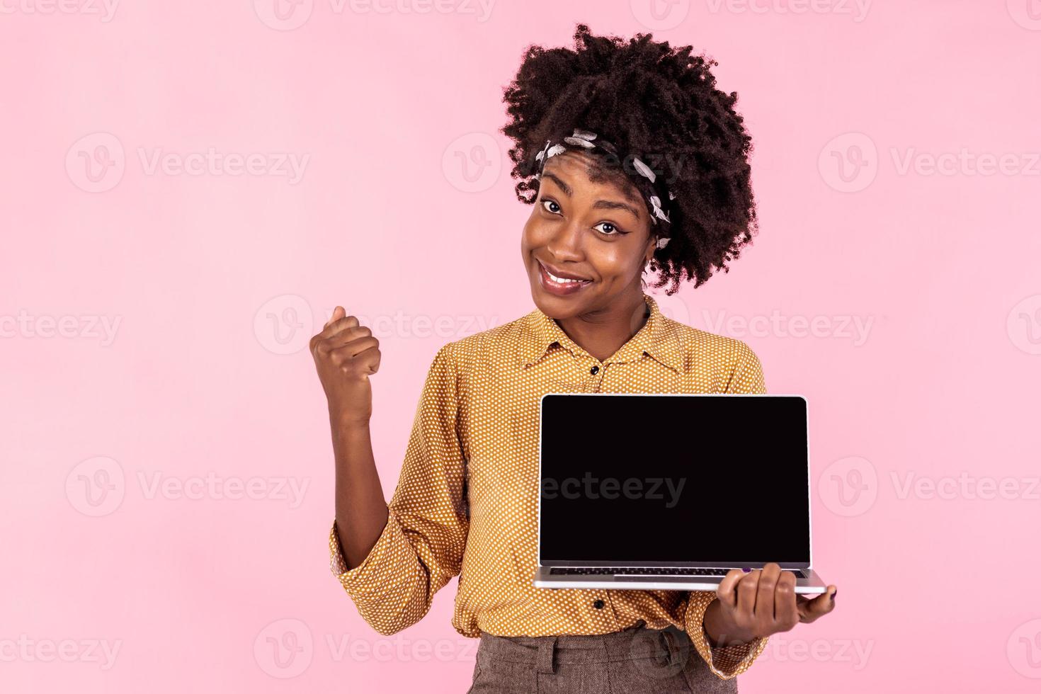 eccitato africano ragazza Tenere il computer portatile con nero schermo. contento attività commerciale donna puntamento su il schermo di il computer portatile. pubblicità concetto foto