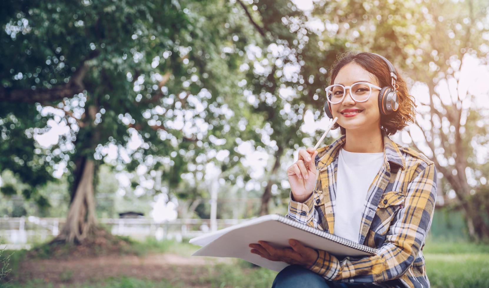 asiatico donna seduta e scrittura nel il giardino foto