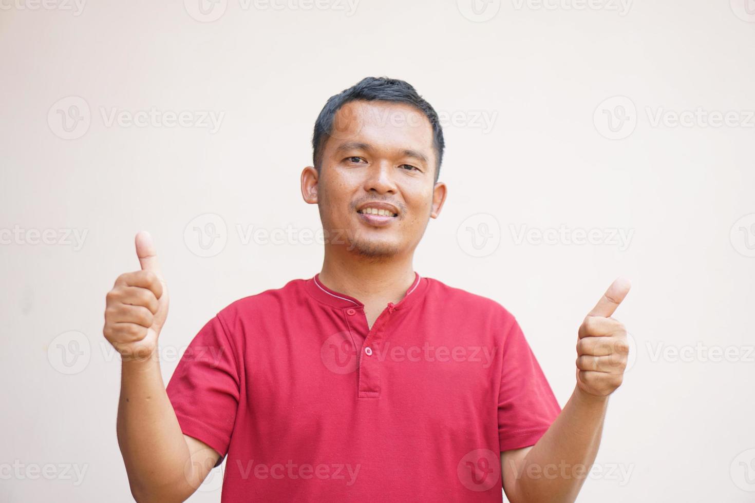 asiatico uomo sorridente felicemente aumentare il tuo mano come un' cartello di ok foto