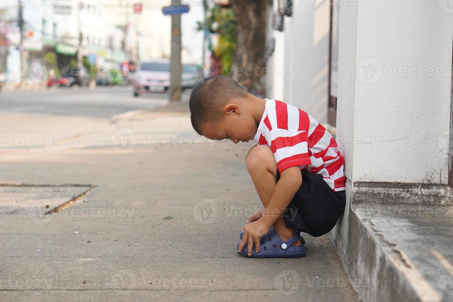 ragazzo seduta su il ciglio della strada in attesa per mamma foto