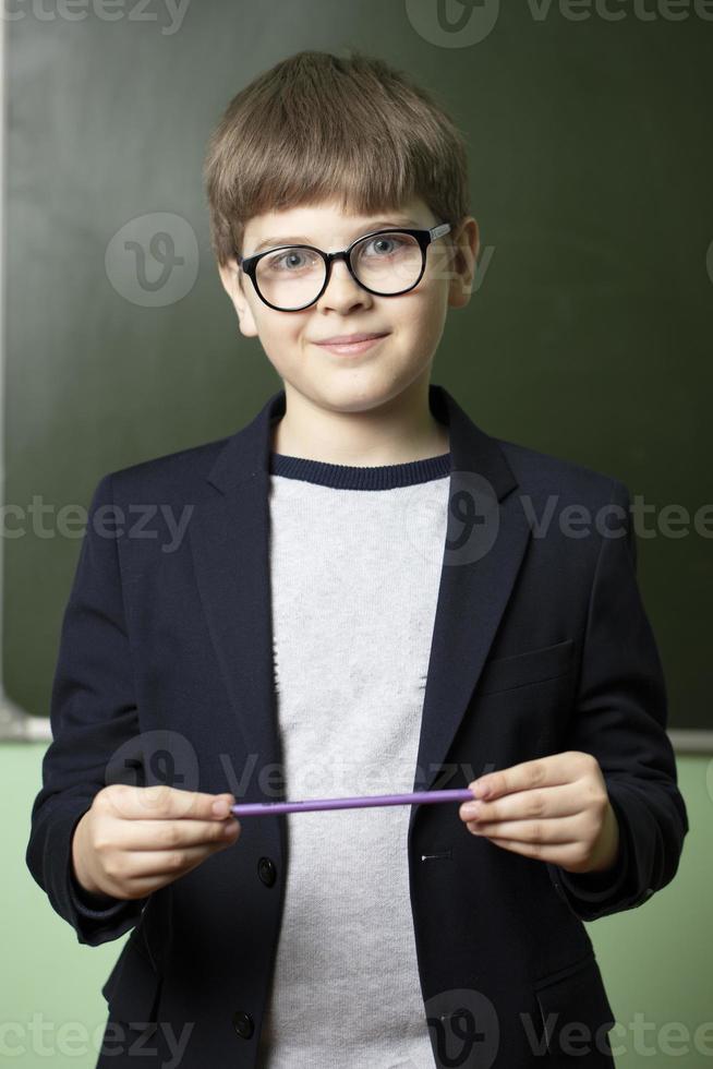 ritratto di un' scolaro a il lavagna. il ragazzo nel il aula è guardare a il telecamera. foto