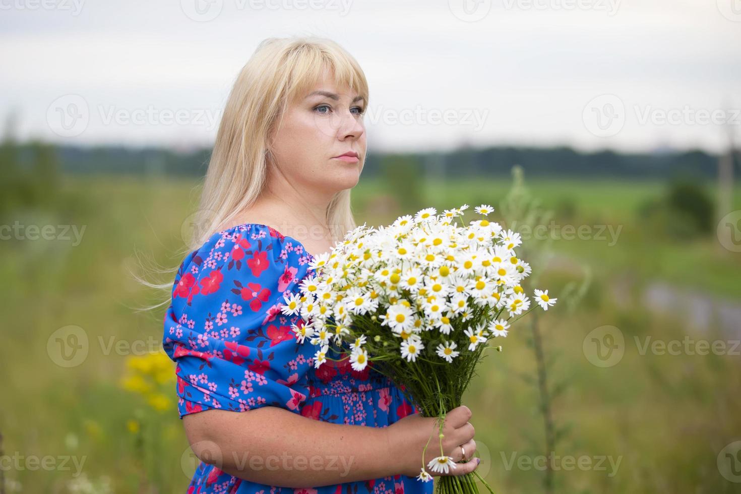 bellissimo più dimensione donna con bianca capelli nel un' estate vestito in posa all'aperto con margherite. paffuto ragazza nel un' prato con fiori. foto