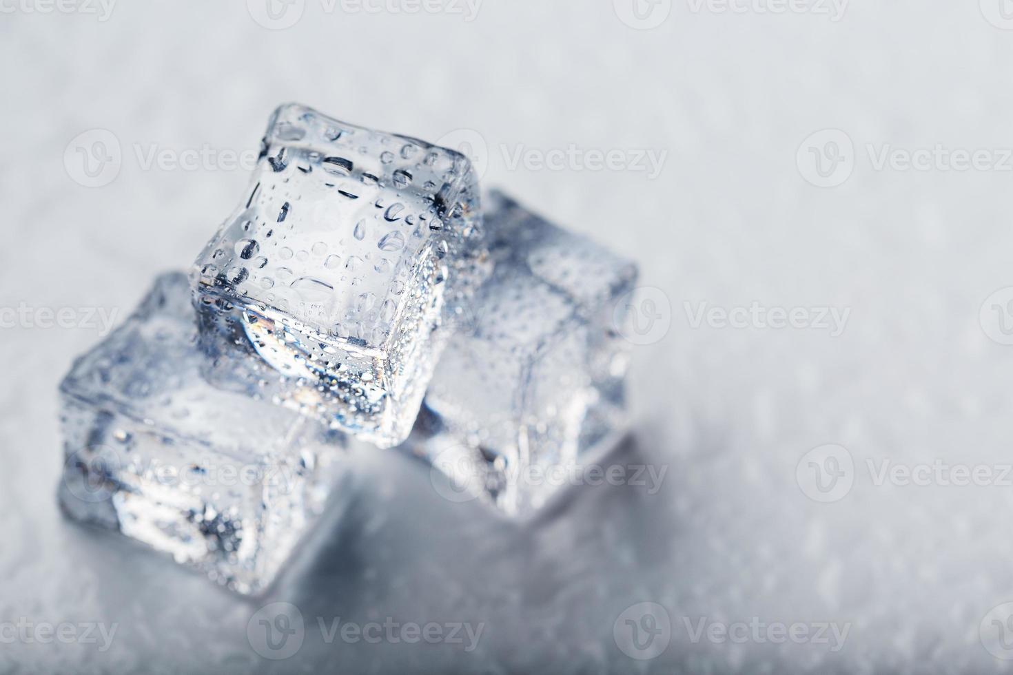 ghiaccio cubi nel il modulo di un' piramide con acqua gocce vicino - su nel macro su un' bianca sfondo. foto