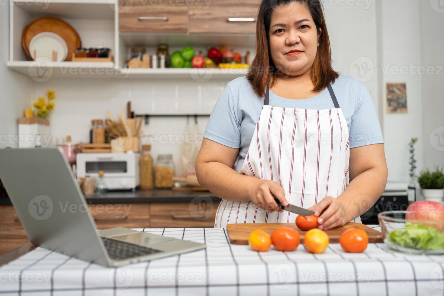 asiatico incinta imparare Come per cucinare salutare pasti a partire dal il Internet nel cucina, Grasso donne preparare un' verdura insalata per dieta cibo e perdere il peso. concetto di salutare mangiare foto