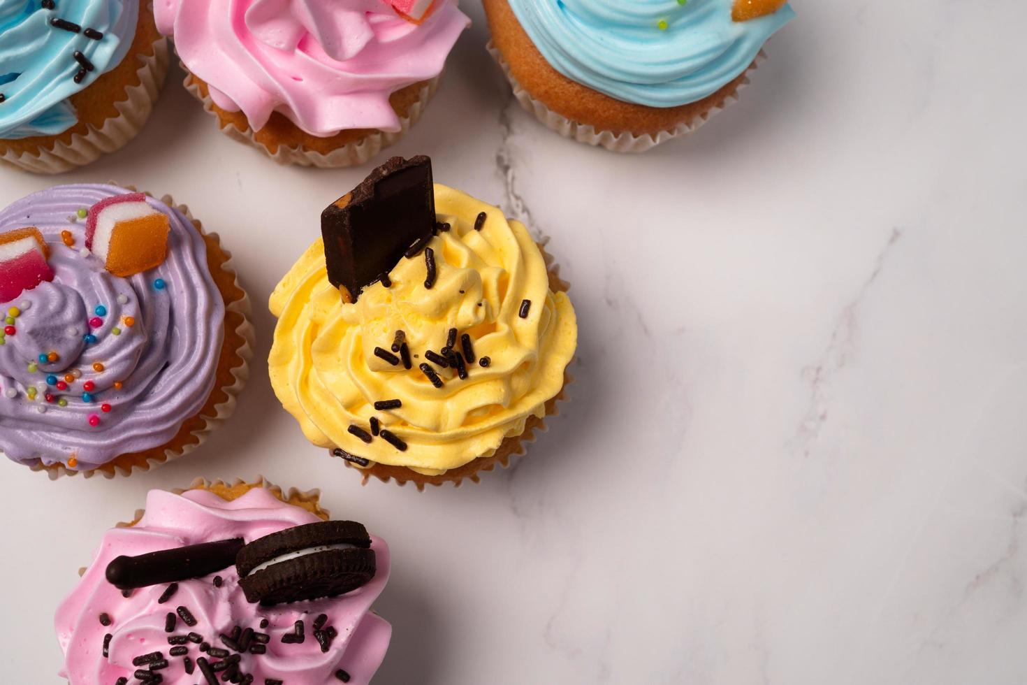 deliziosi cupcakes fatti in casa con crema colorata e topping con caramelle e biscotti al cioccolato. dolce fatto in casa per le vacanze autunnali foto