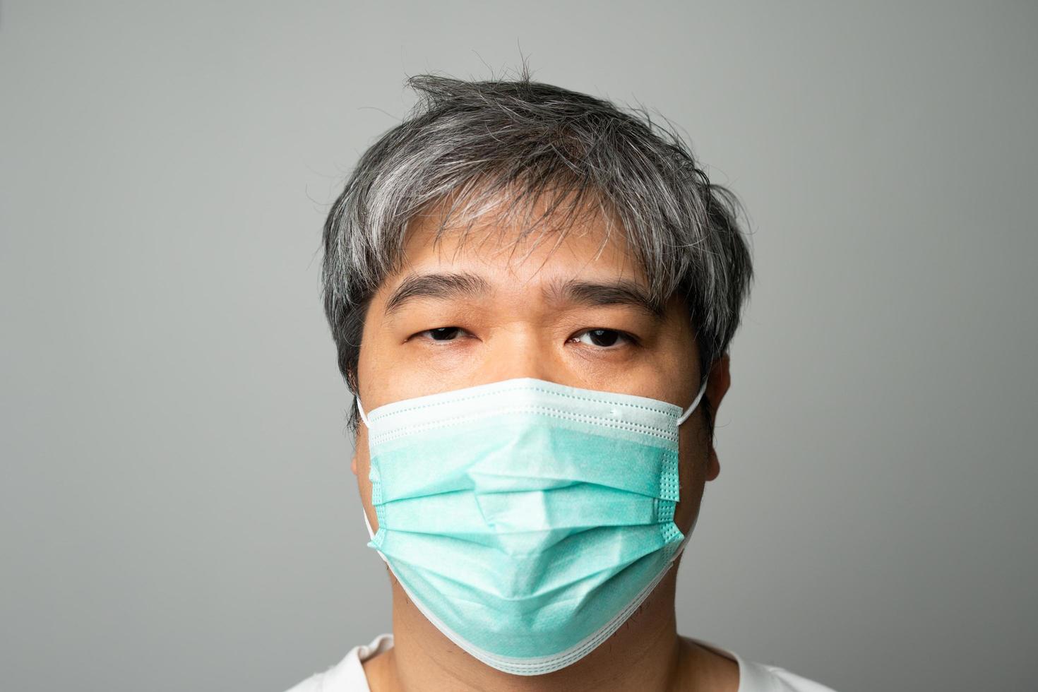 uomo asiatico malato che indossa una maschera medica e dolore alla spalla e stress. concetto di protezione da coronavirus pandemico e malattie respiratorie foto