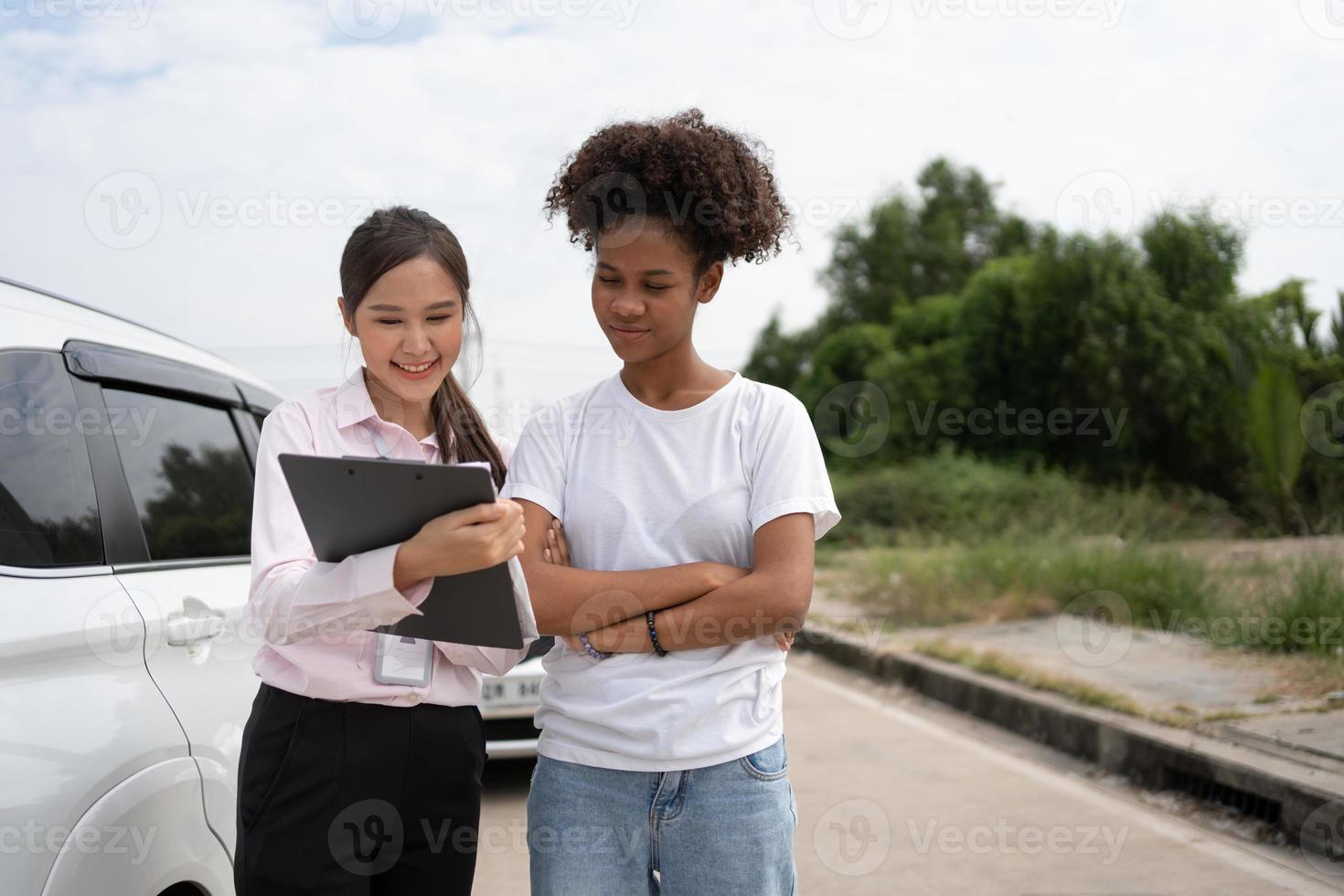 donne autisti parlare per assicurazione agente per l'esame danneggiato auto e cliente controlli su il rapporto Richiesta modulo dopo un incidente. concetto di assicurazione, consigli auto riparazione negozio e auto traffico incidenti. foto