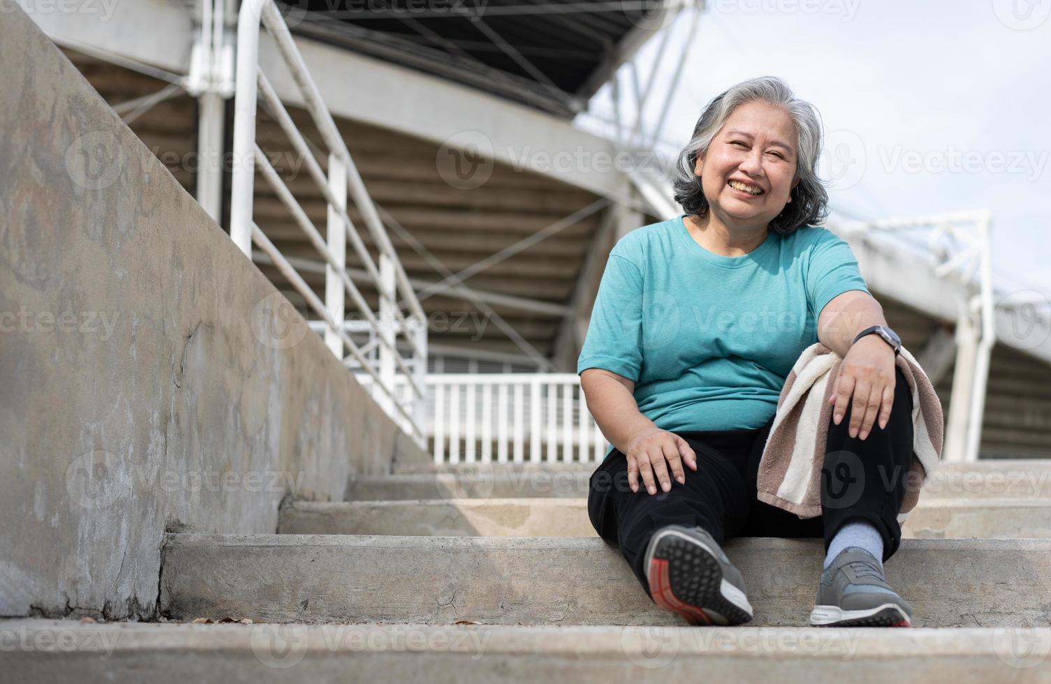 contento e Sorridi anziano asiatico donna seduta su le scale per riposo dopo allenamento, jogging su mattina, anziano esercizio all'aperto per bene sano. concetto di assistenza sanitaria e attivo stile di vita per salutare foto