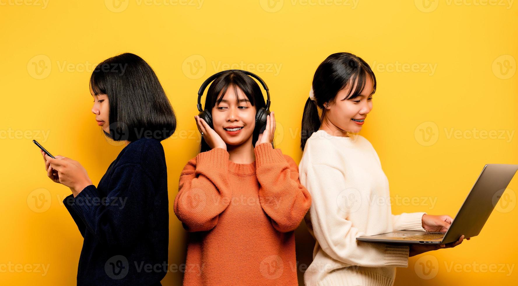 Due asiatico donne Lavorando su il computer portatile e Telefono. a il stesso tempo Due di loro erano comunicare in linea e mostrando contento sorrisi. e ascolta per musica in giro persone e amici in linea comunicazione foto