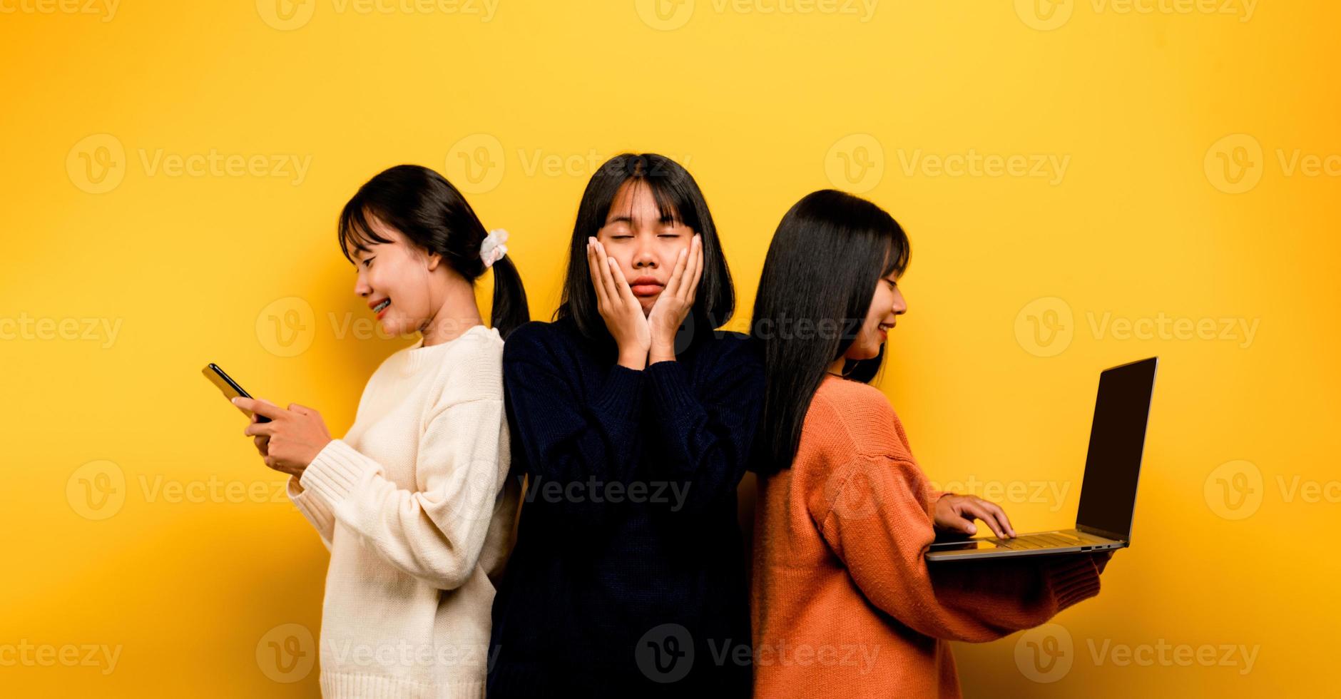 Due asiatico donne Lavorando su il computer portatile e Telefono. a il stesso tempo Due di loro erano comunicare in linea e mostrando contento sorrisi. e fa non cura di il persone in giro lui e il suo amici in linea foto