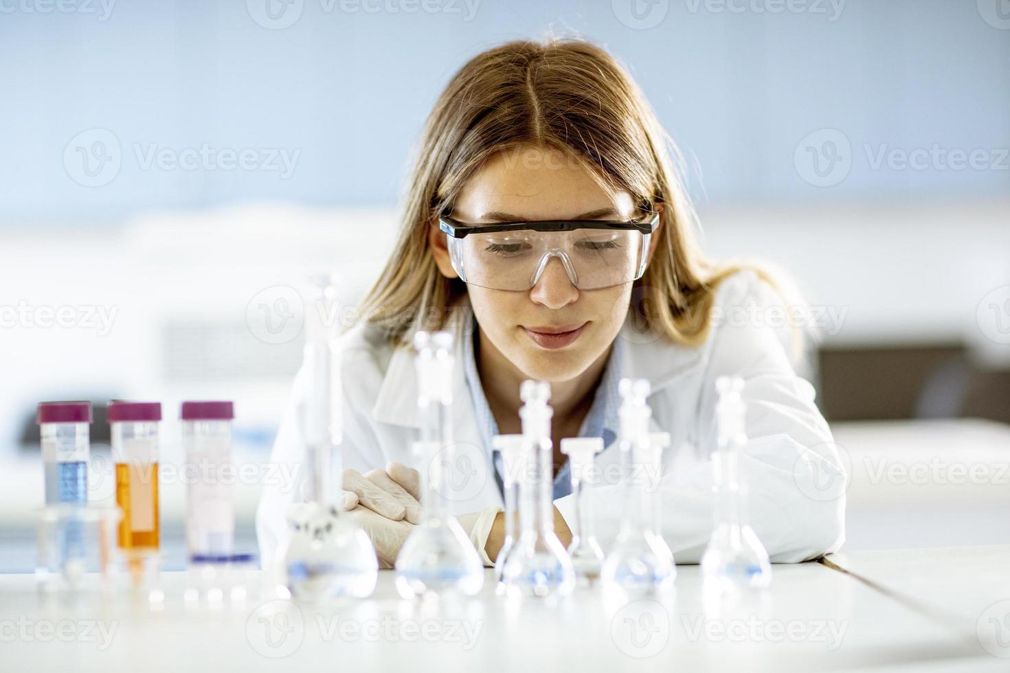 ricercatore medico o scientifico femminile guardando una boccetta con soluzioni in un laboratorio foto