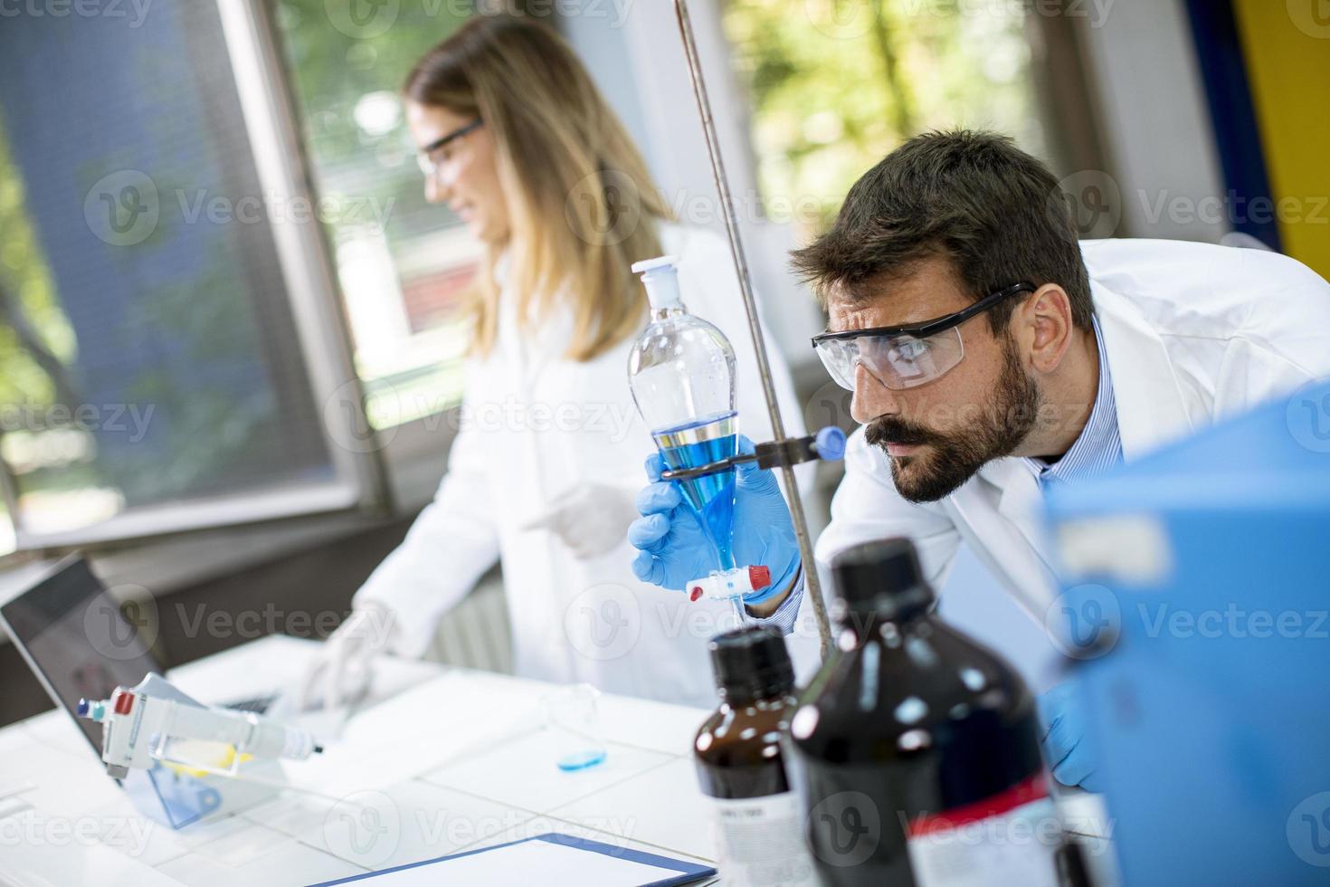 ricercatori che lavorano con il liquido blu all'imbuto separatore foto