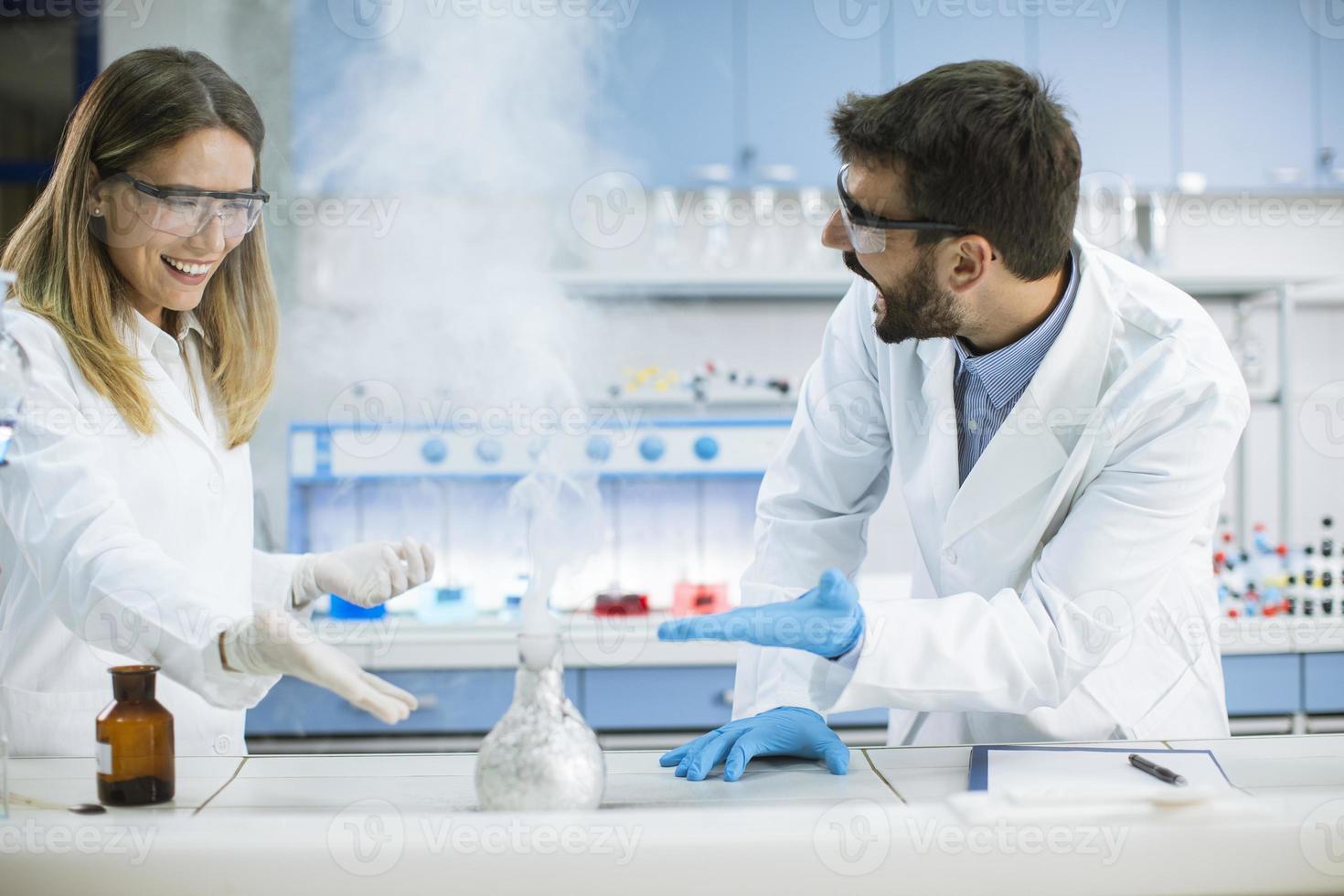 ricercatori che fanno esperimenti con il fumo su un tavolo di un laboratorio chimico foto