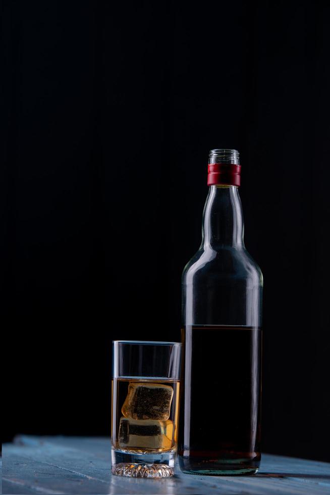 natura morta con vetro e bottiglia di alcol sul tavolo di legno foto