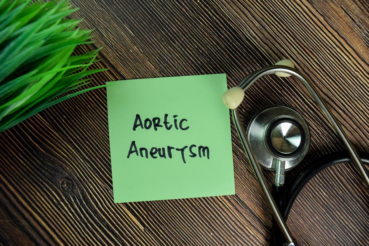 aneurisma aortico scritto su una nota adesiva isolata sul tavolo di legno foto