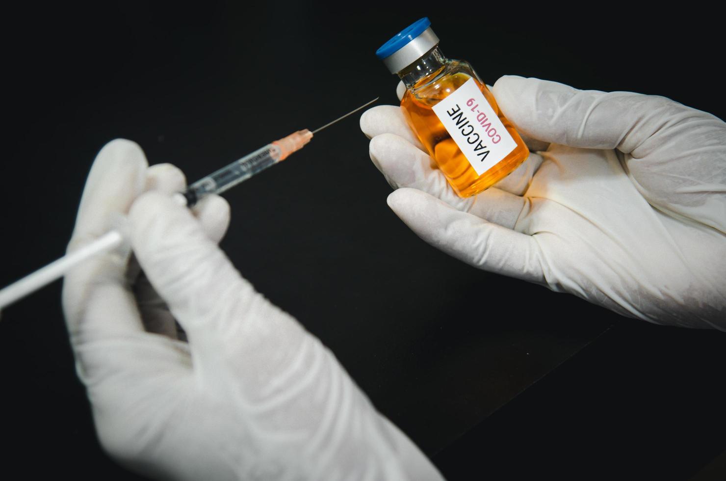 persona in possesso di una siringa e di un vaccino covid foto