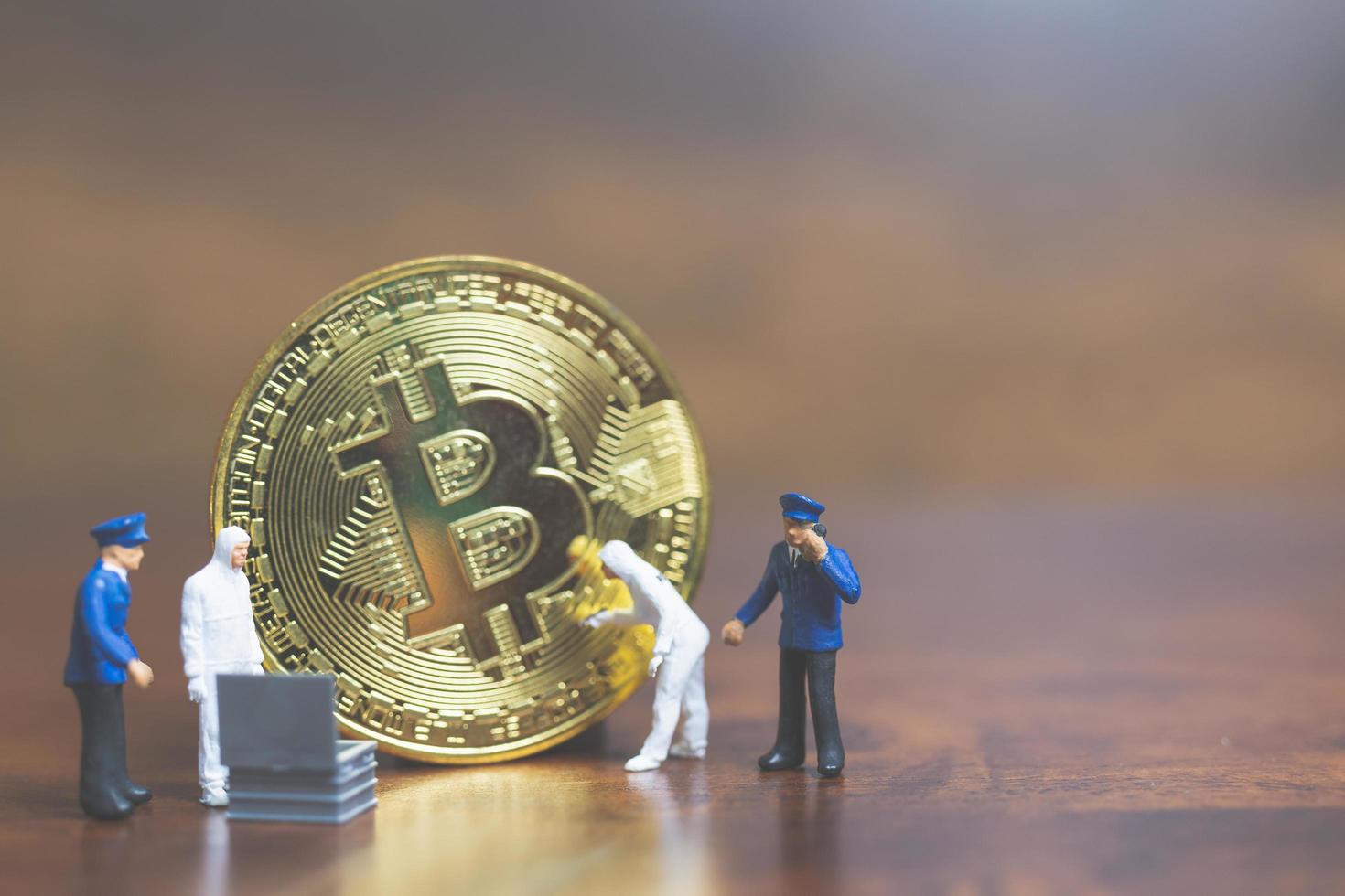 polizia in miniatura e detective in piedi davanti alla criptovaluta bitcoin, concetto di criminalità informatica foto