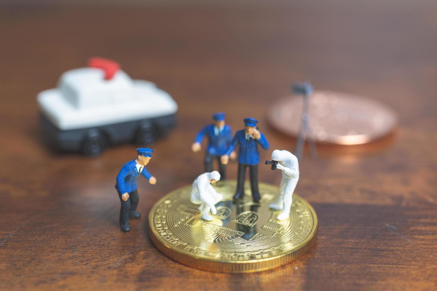 polizia in miniatura e detective in piedi davanti alla criptovaluta bitcoin, concetto di criminalità informatica foto