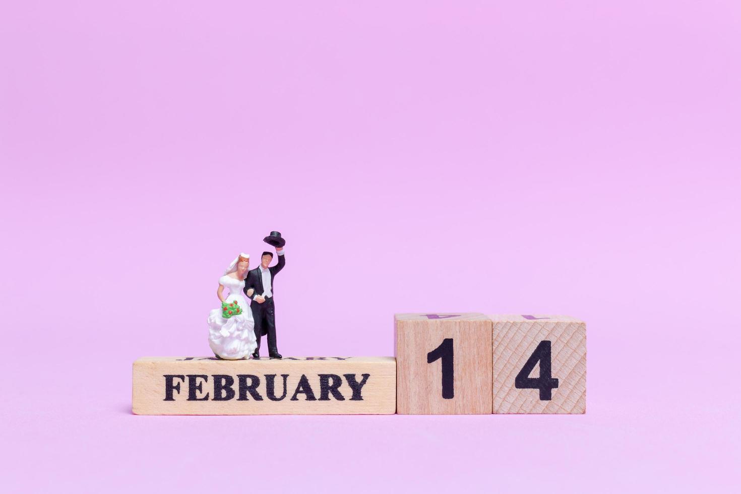 sposa e sposo in miniatura su uno sfondo rosa, il giorno di San Valentino e il concetto di matrimonio foto