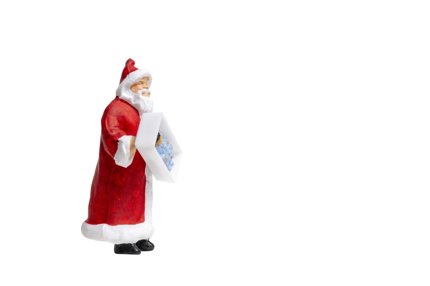 Babbo Natale in miniatura che tiene una confezione regalo isolata su uno sfondo bianco foto