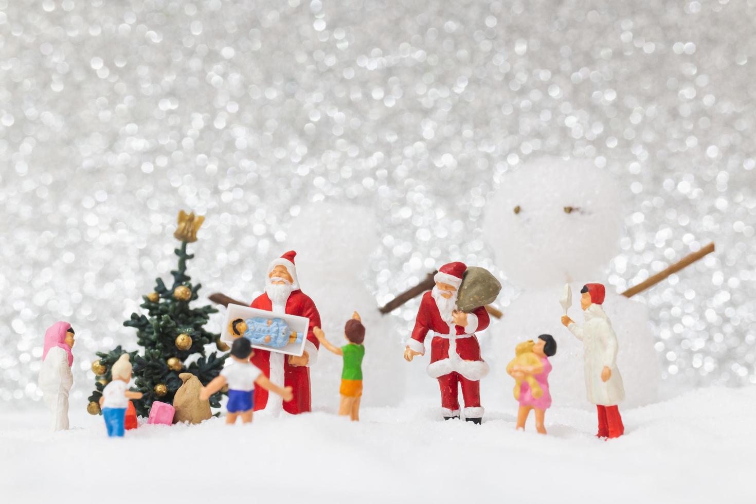 Babbo Natale in miniatura e bambini con uno sfondo di neve, Natale e felice anno nuovo concetto foto
