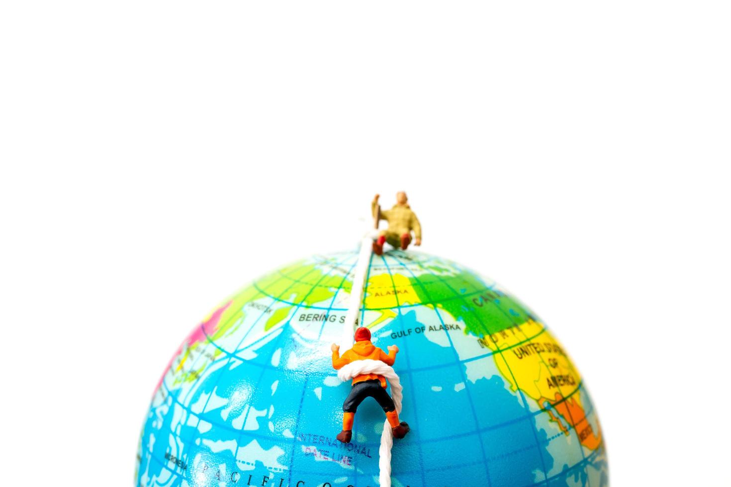 escursionisti in miniatura che si arrampicano sul concetto di globo, sport e tempo libero foto