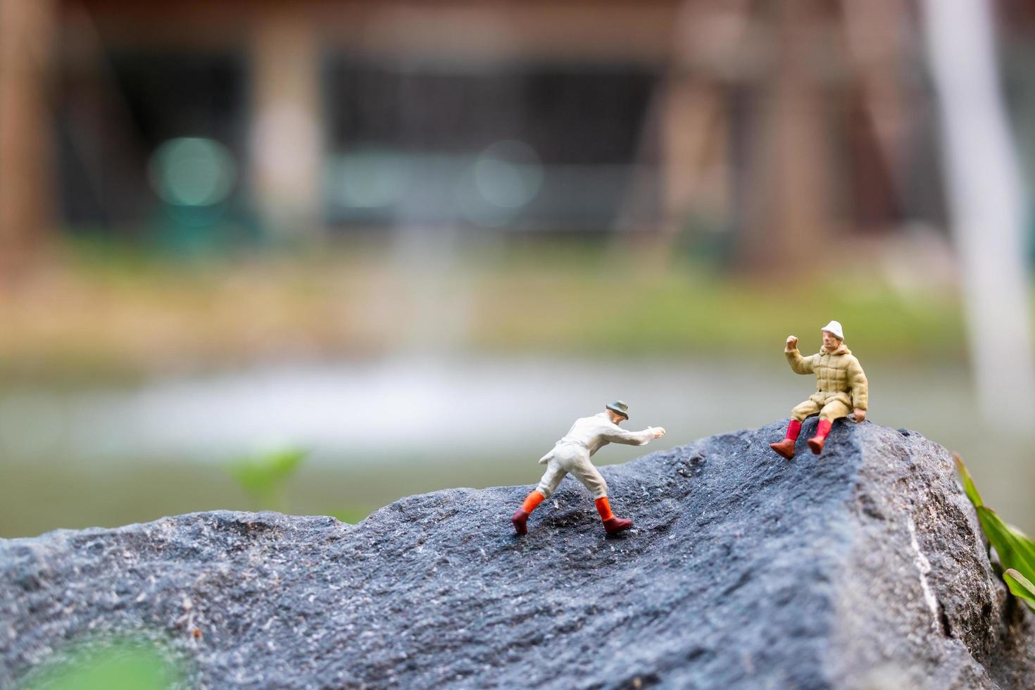 escursionisti in miniatura che si arrampicano su una roccia, sport e concetto di tempo libero foto