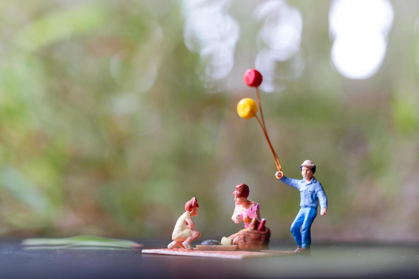 famiglia in miniatura seduta su una stuoia durante un picnic in un parco foto