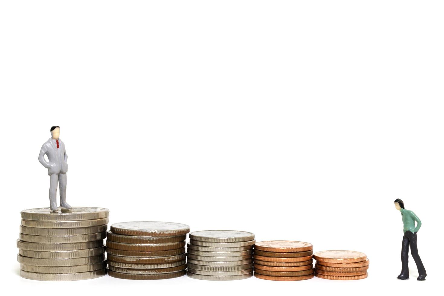 uomini d'affari in miniatura con una pila di monete su uno sfondo bianco foto