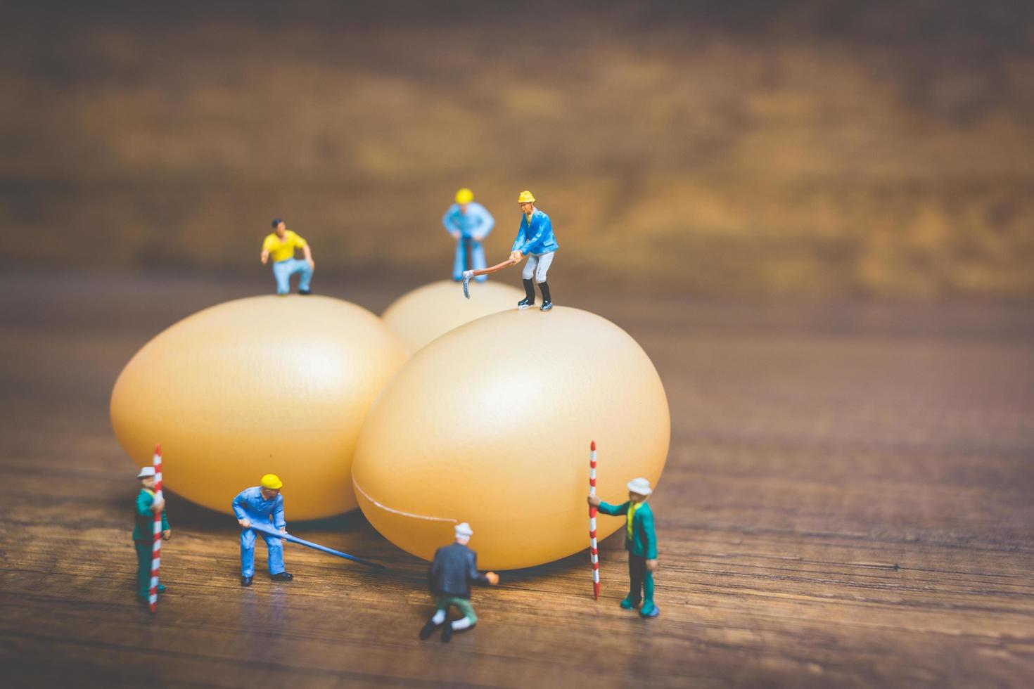 persone in miniatura che lavorano sulle uova di Pasqua per la Pasqua foto