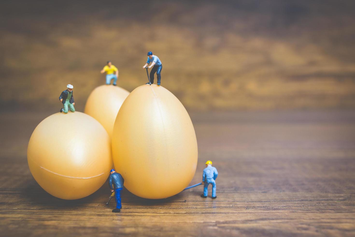 persone in miniatura che lavorano sulle uova di Pasqua per la Pasqua foto