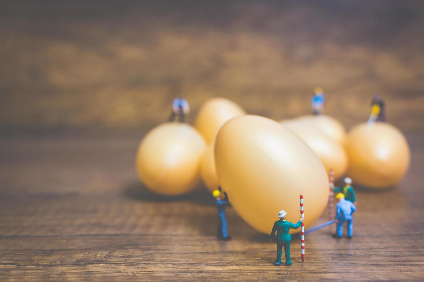 persone in miniatura che lavorano sulle uova di Pasqua per la Pasqua foto