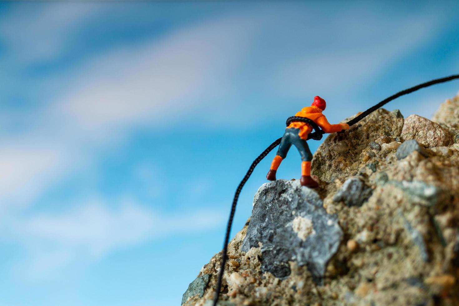 escursionisti in miniatura che si arrampicano su una roccia, sport e concetto di tempo libero foto