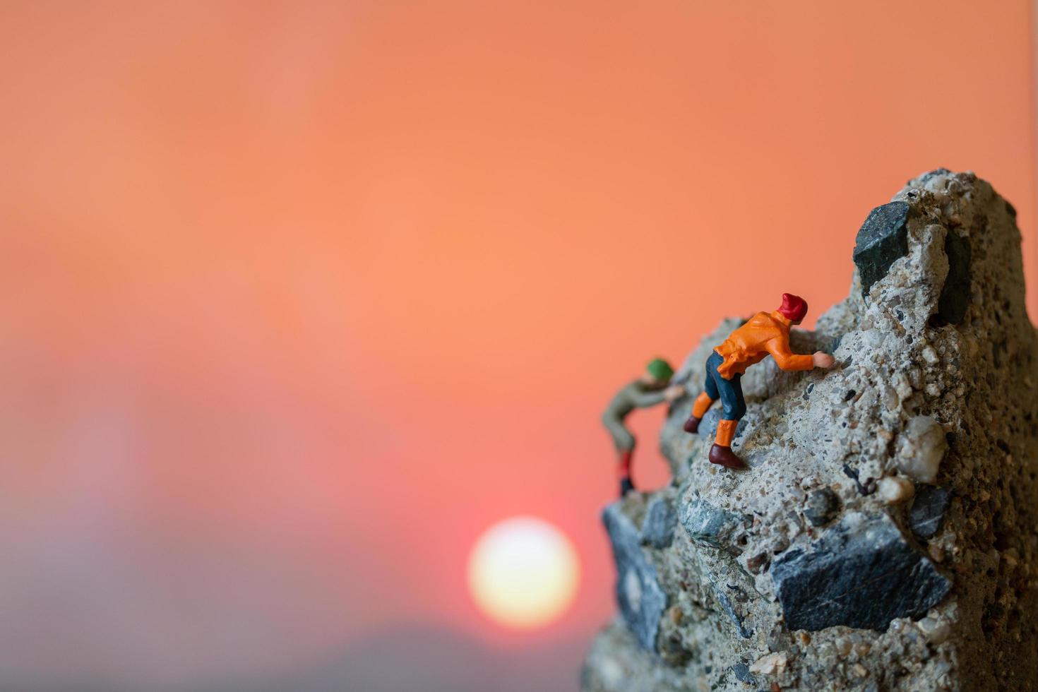 escursionisti in miniatura che si arrampicano su una roccia, sport e concetto di tempo libero foto